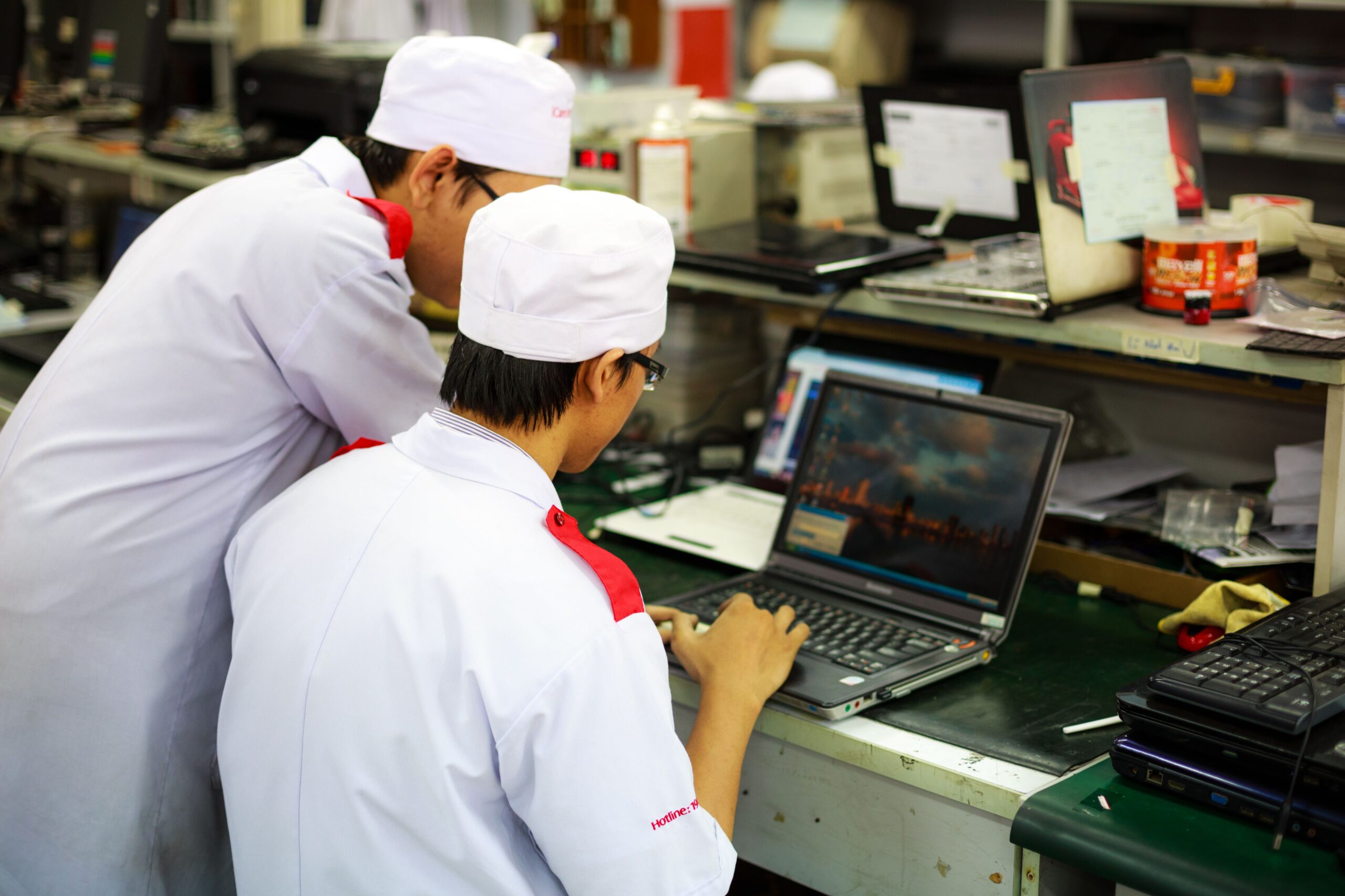 Técnicos industriales realizando ajustes y mantenimiento de equipos informáticos dentro de una planta de producción Técnicos industriales realizando ajustes y mantenimiento de equipos informáticos dentro de una planta de producción