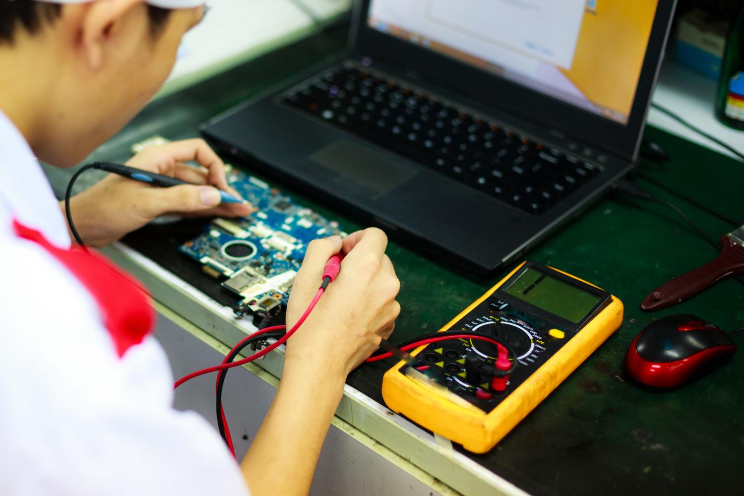 Técnico especializado realizando una auditoría de hardware en un portátil con herramientas de medición Técnico especializado realizando una auditoría de hardware en un portátil con herramientas de medición