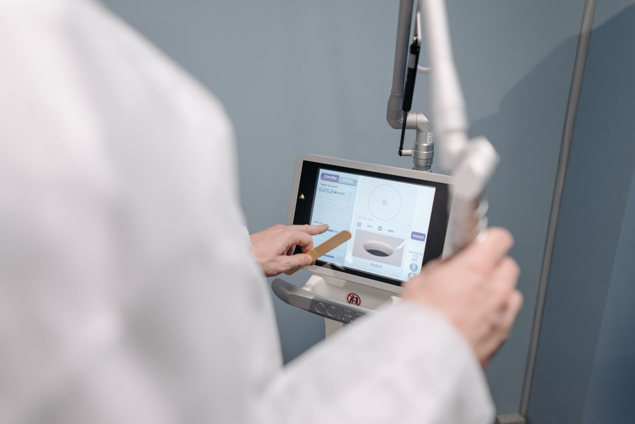 Profesional médico operando una máquina láser con interfaz de monitor táctil en clínica Profesional médico operando una máquina láser con interfaz de monitor táctil en clínica