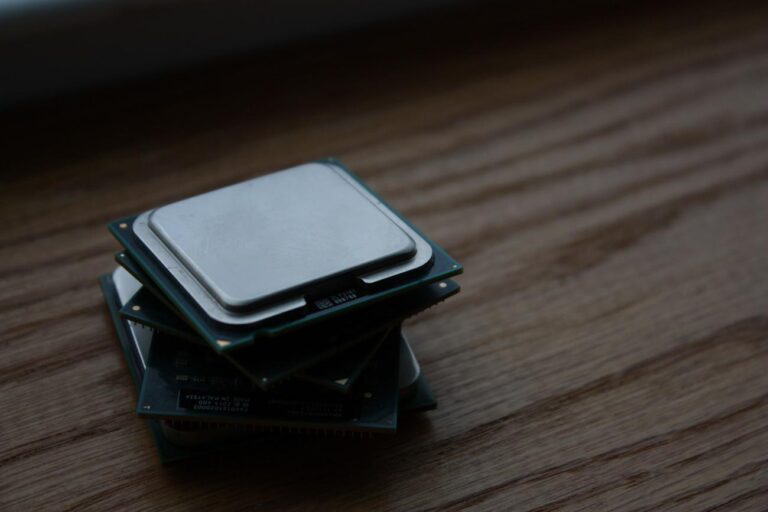 Primer plano de una pila de procesadores CPU apilados sobre una superficie de madera, mostrando los disipadores de calor integrados y los sustratos verdes de los chips, ideal para ilustrar el concepto de tarjetas CPU y procesadores.