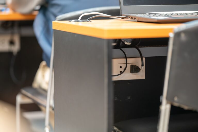 Escritorio moderno con portátil y cable de alimentación conectado al enchufe, ideal para ilustrar consumo fantasma