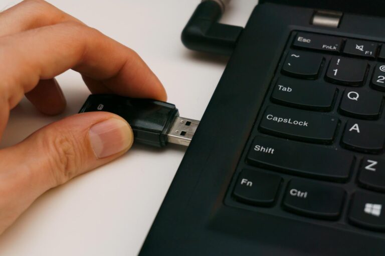 Persona insertando un pendrive USB en el puerto de un ordenador portátil, representando el intento de conectar un dispositivo.