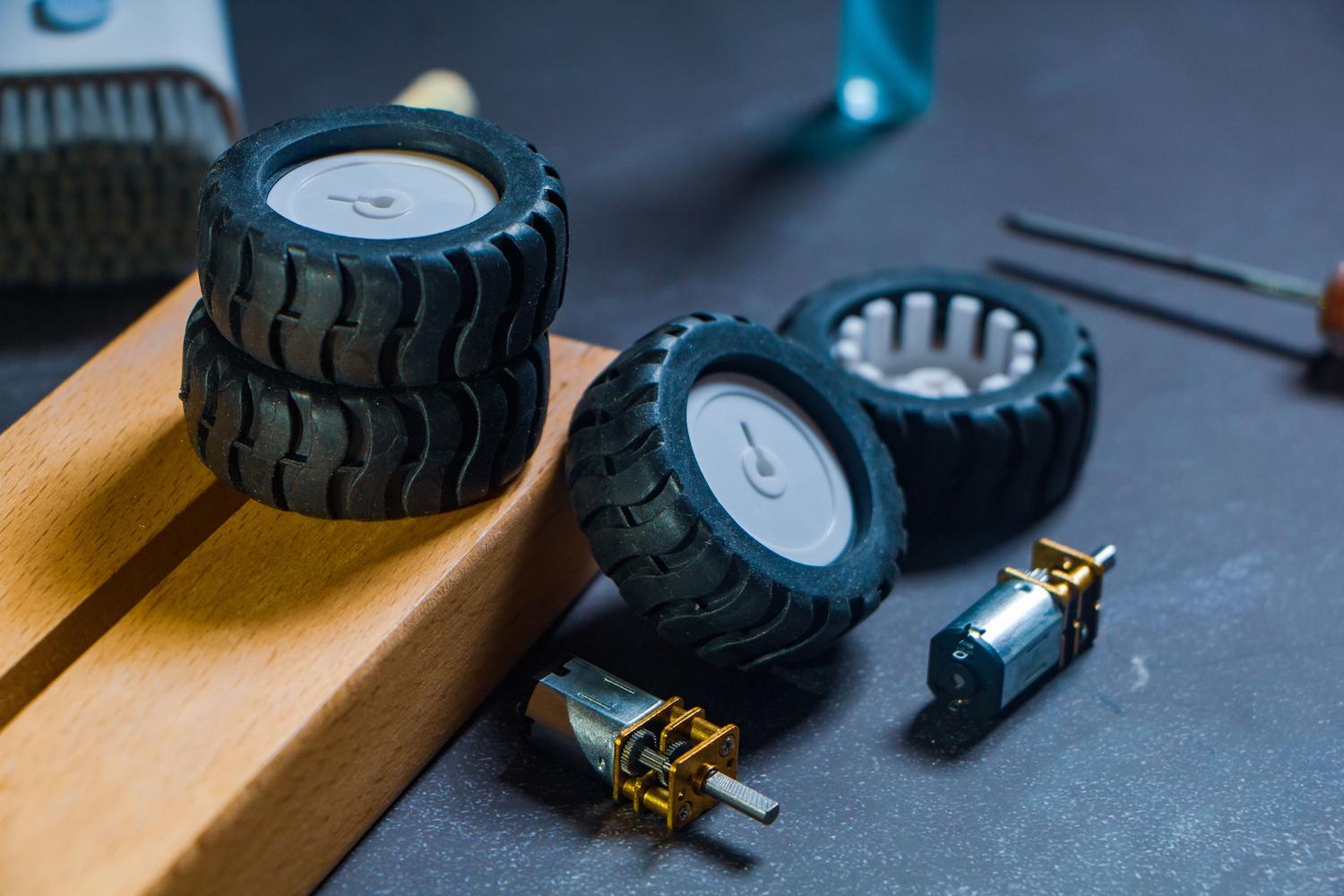 Primer plano de piezas de un kit de robótica, incluyendo ruedas y motores, ideal para enseñar mecánica básica. Primer plano de piezas de un kit de robótica, incluyendo ruedas y motores, ideal para enseñar mecánica básica.