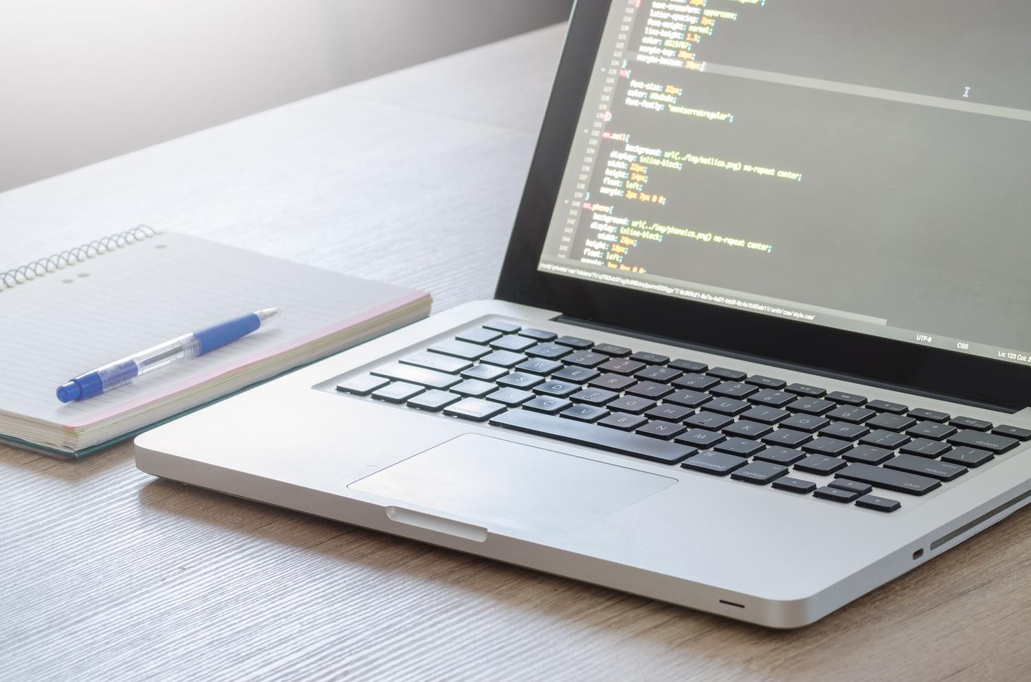 Planificación de proyecto Android Espacio de trabajo de un desarrollador con ordenador portátil, cuaderno y bolígrafo para la planificación de proyectos.