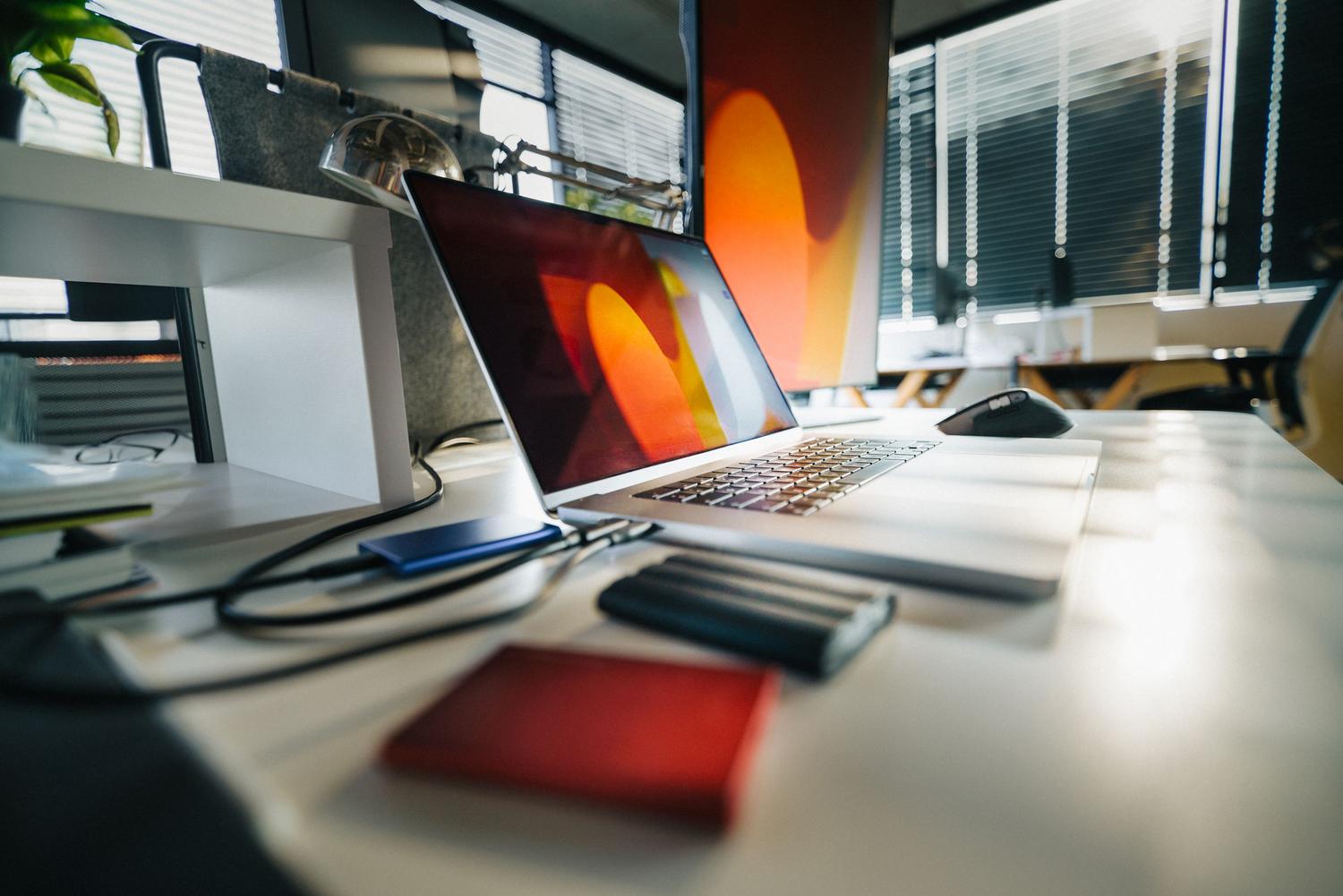 Escritorio de oficina moderno con portátil y discos externos, representando la importancia de realizar copias de seguridad antes de la instalación. Escritorio de oficina moderno con portátil y discos externos, representando la importancia de realizar copias de seguridad antes de la instalación.