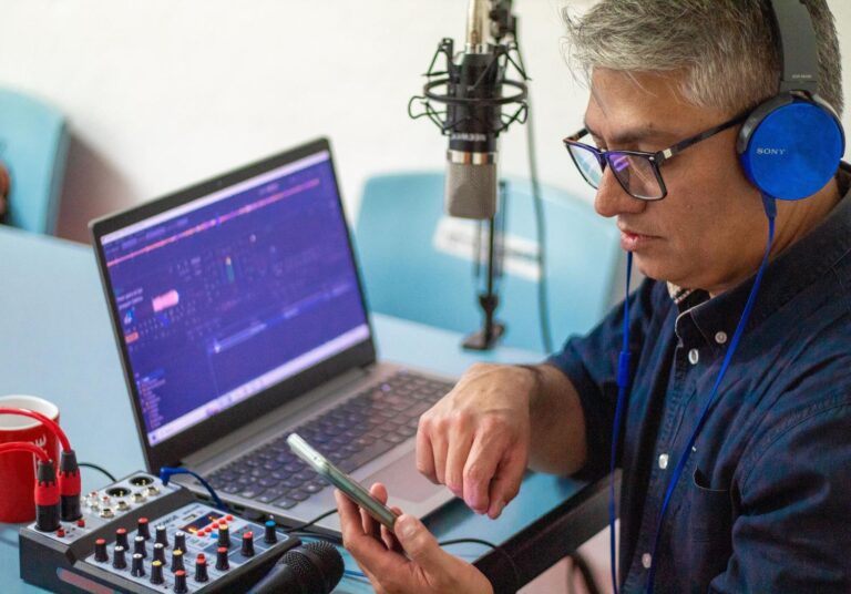 Hombre transmitiendo en una radio por internet con equipo profesional, ordenador y mesa de mezclas
