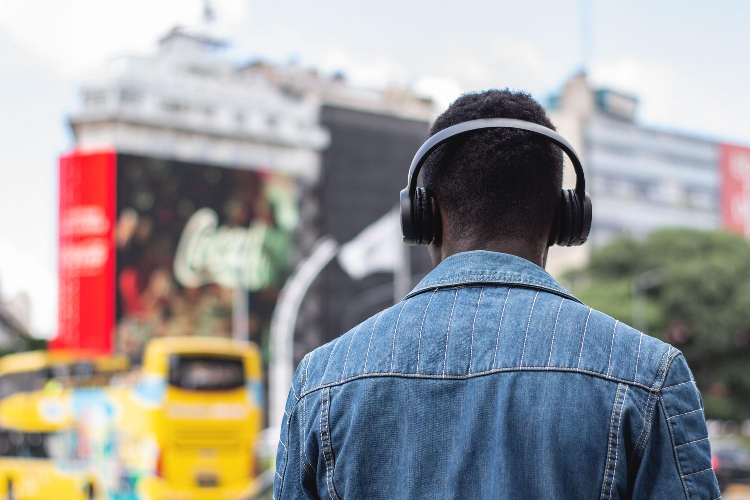 Persona escuchando una emisora de radio online a través de un smartphone y auriculares en la calle Persona escuchando una emisora de radio online a través de un smartphone y auriculares en la calle