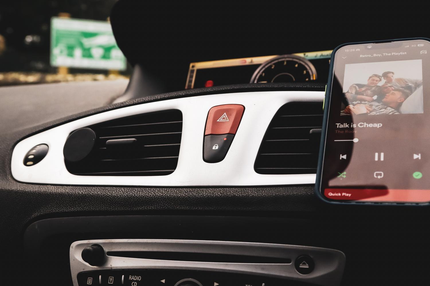Smartphone montado en el salpicadero de un coche mostrando una aplicación de música, transformando el vehículo en un centro multimedia. Smartphone montado en el salpicadero de un coche mostrando una aplicación de música, transformando el vehículo en un centro multimedia.