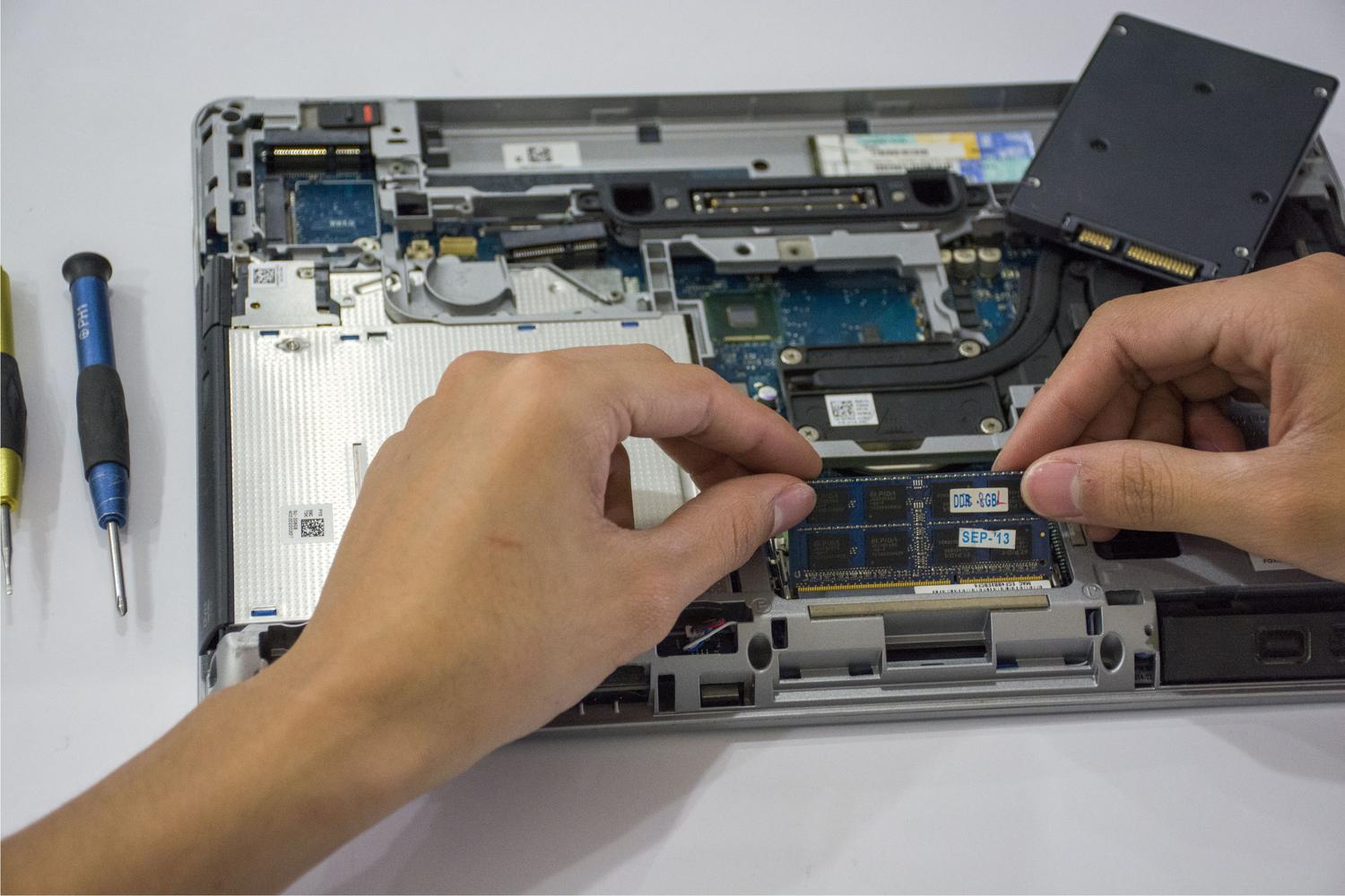 Técnico instalando un módulo de memoria RAM en el interior de un ordenador portátil, ideal para secciones de actualización de hardware. Técnico instalando un módulo de memoria RAM en el interior de un ordenador portátil, ideal para secciones de actualización de hardware.