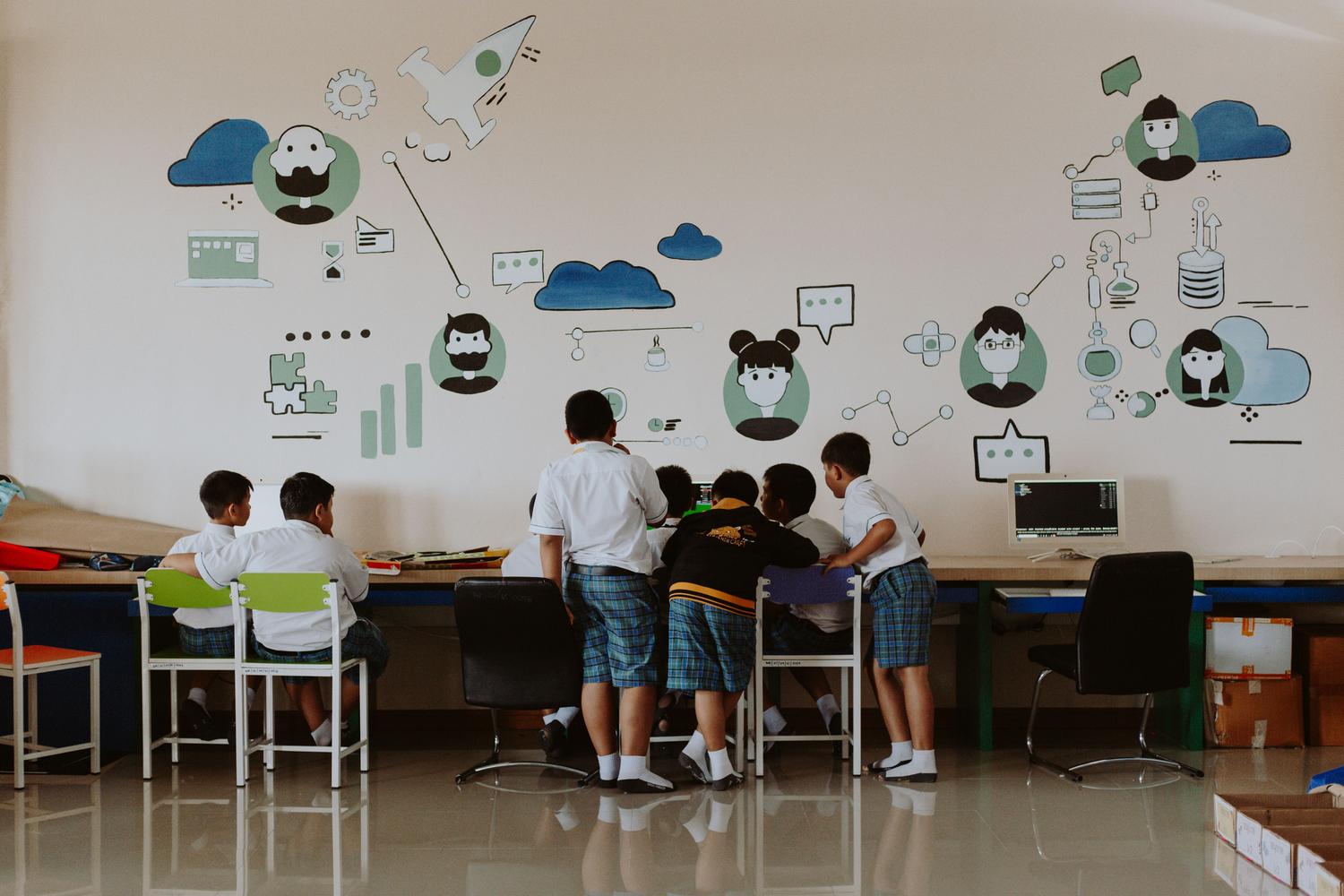 Estudiantes colaborando en un laboratorio de informática colorido con murales representativos de inteligencia artificial. Estudiantes colaborando en un laboratorio de informática colorido con murales representativos de inteligencia artificial.