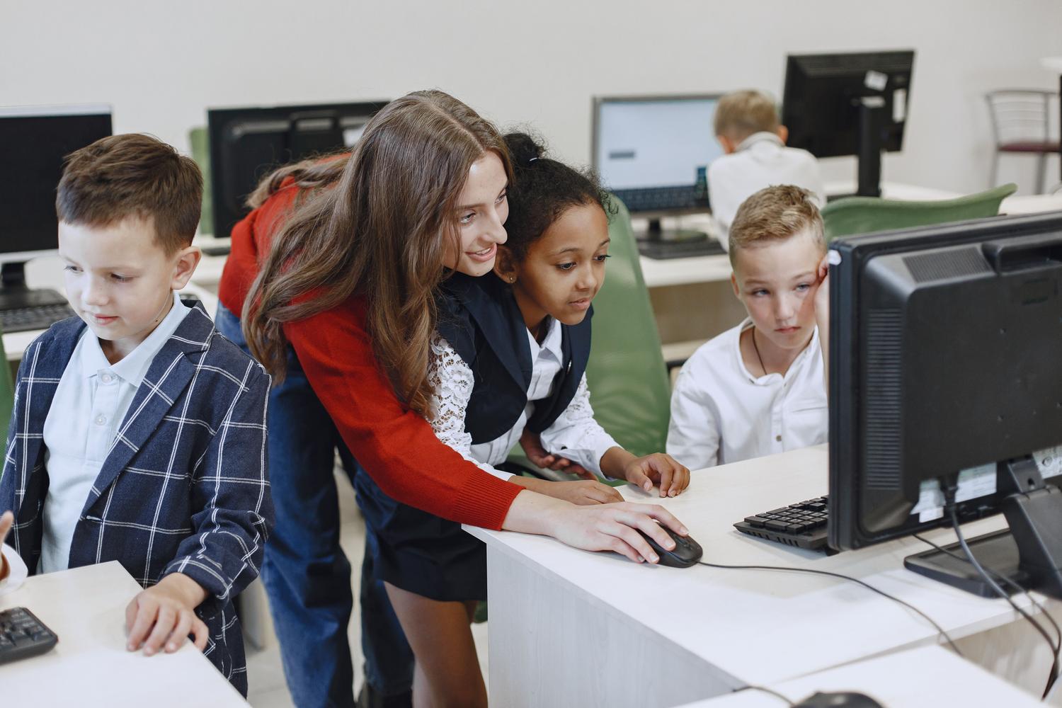 Una profesora guiando a una alumna en el uso de un ordenador en un aula de tecnología. Una profesora guiando a una alumna en el uso de un ordenador en un aula de tecnología.
