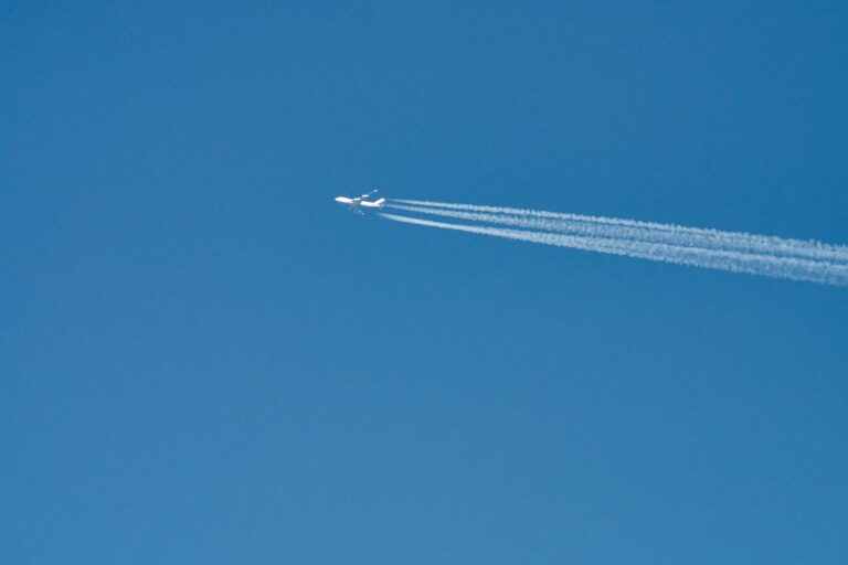 Avión comercial dejando una estela blanca en un cielo azul despejado, ilustrando la curiosidad por el tráfico aéreo.