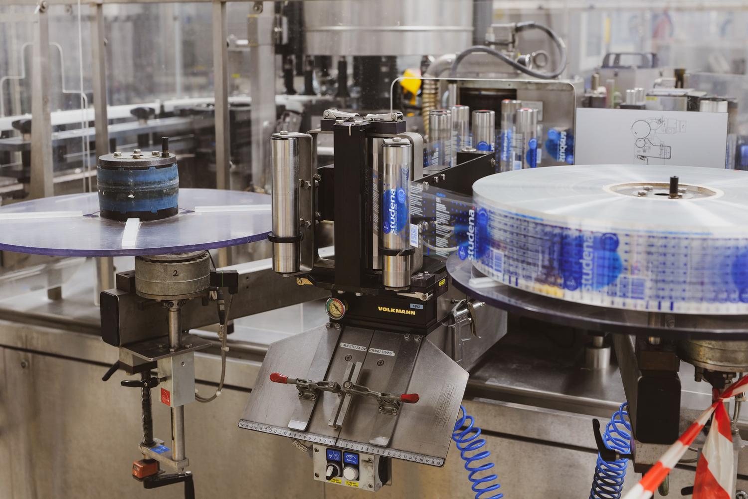 Detalle tƩcnico de una mƔquina etiquetadora automatizada procesando botellas de vidrio Detalle tƩcnico de una mƔquina etiquetadora automatizada procesando botellas de vidrio