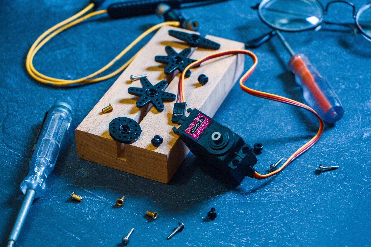 Banco de trabajo de un maker con herramientas, servomotores y componentes electrĂłnicos, representando el entorno de desarrollo de robĂłtica. Banco de trabajo de un maker con herramientas, servomotores y componentes electrĂłnicos, representando el entorno de desarrollo de robĂłtica.