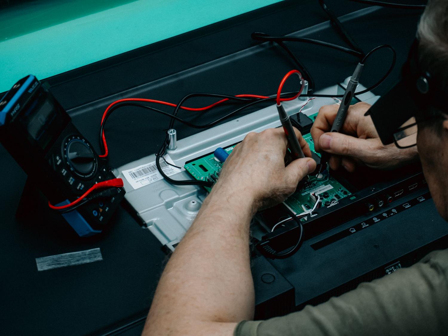 Técnico utilizando un multímetro digital para verificar la tensión en un circuito electrónico, representando la importancia de la estabilidad eléctrica y el VREFBUF. Técnico utilizando un multímetro digital para verificar la tensión en un circuito electrónico, representando la importancia de la estabilidad eléctrica y el VREFBUF.