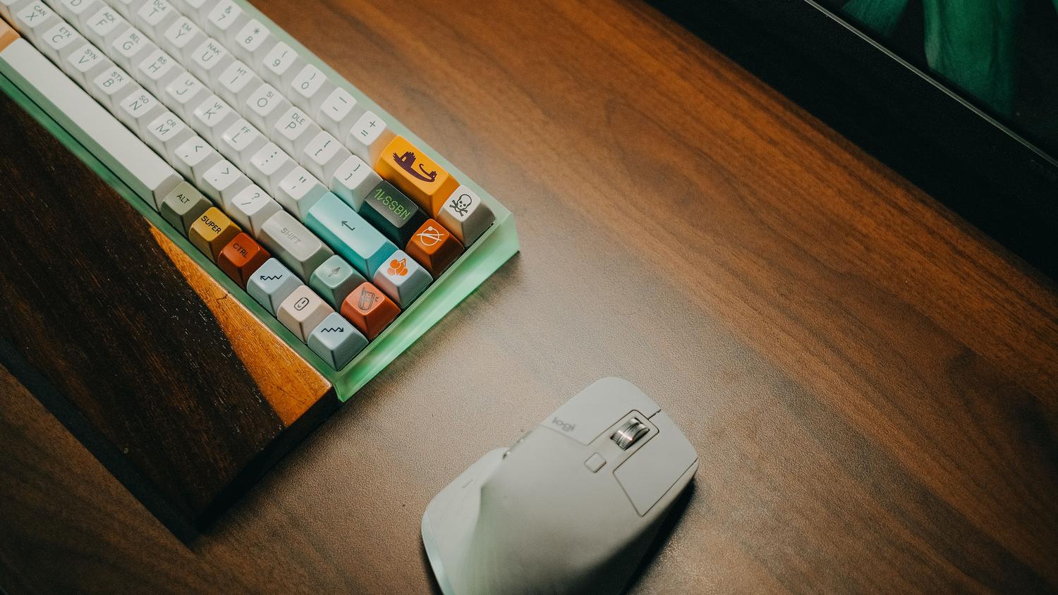 Accesorios esenciales para el PC Teclado mecánico colorido y ratón de alta precisión sobre una mesa de madera, destacando los accesorios esenciales para mejorar la ergonomía.