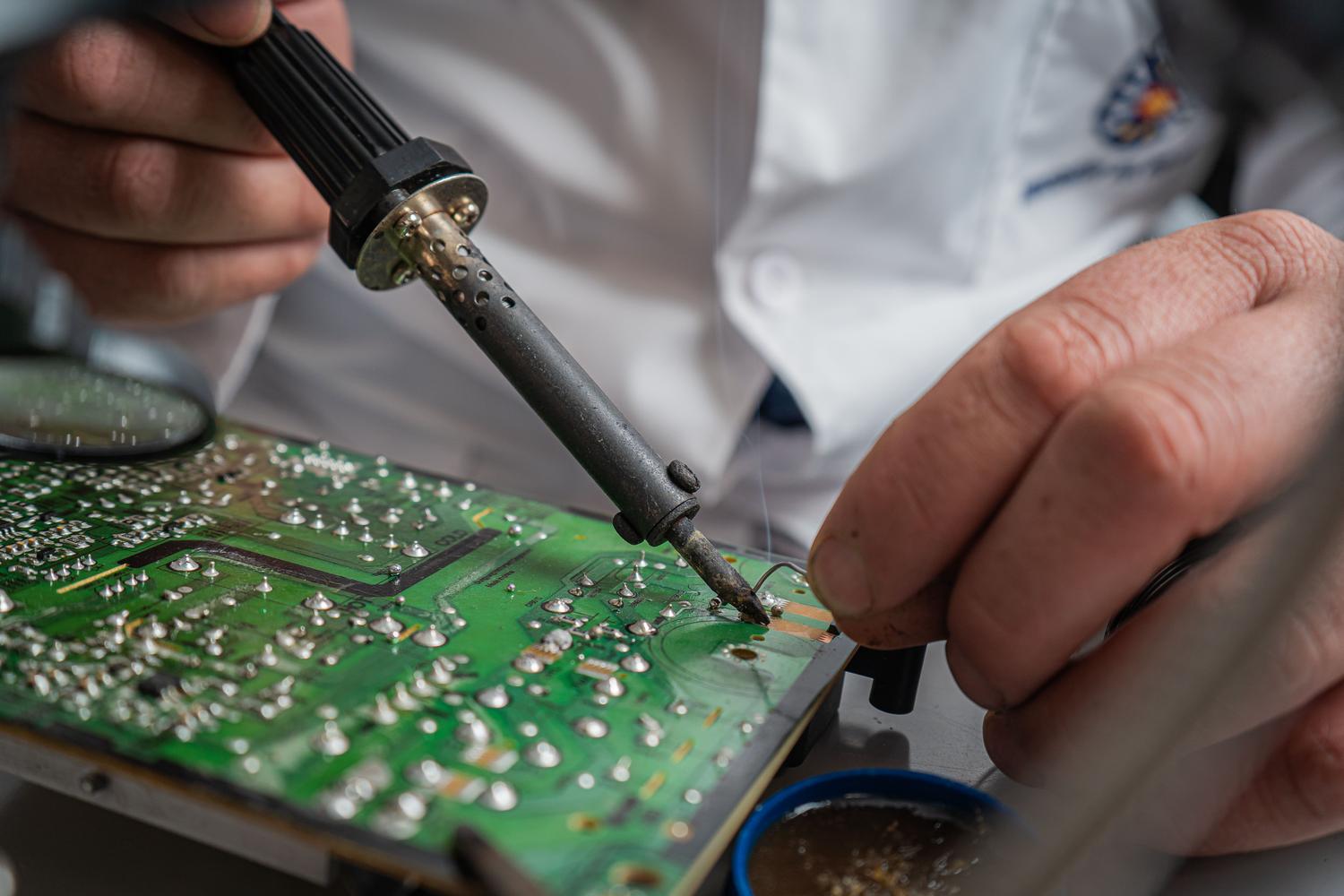 Primer plano de un proceso de microsoldadura para la reparación de pistas conductoras en una placa electrónica. Primer plano de un proceso de microsoldadura para la reparación de pistas conductoras en una placa electrónica.