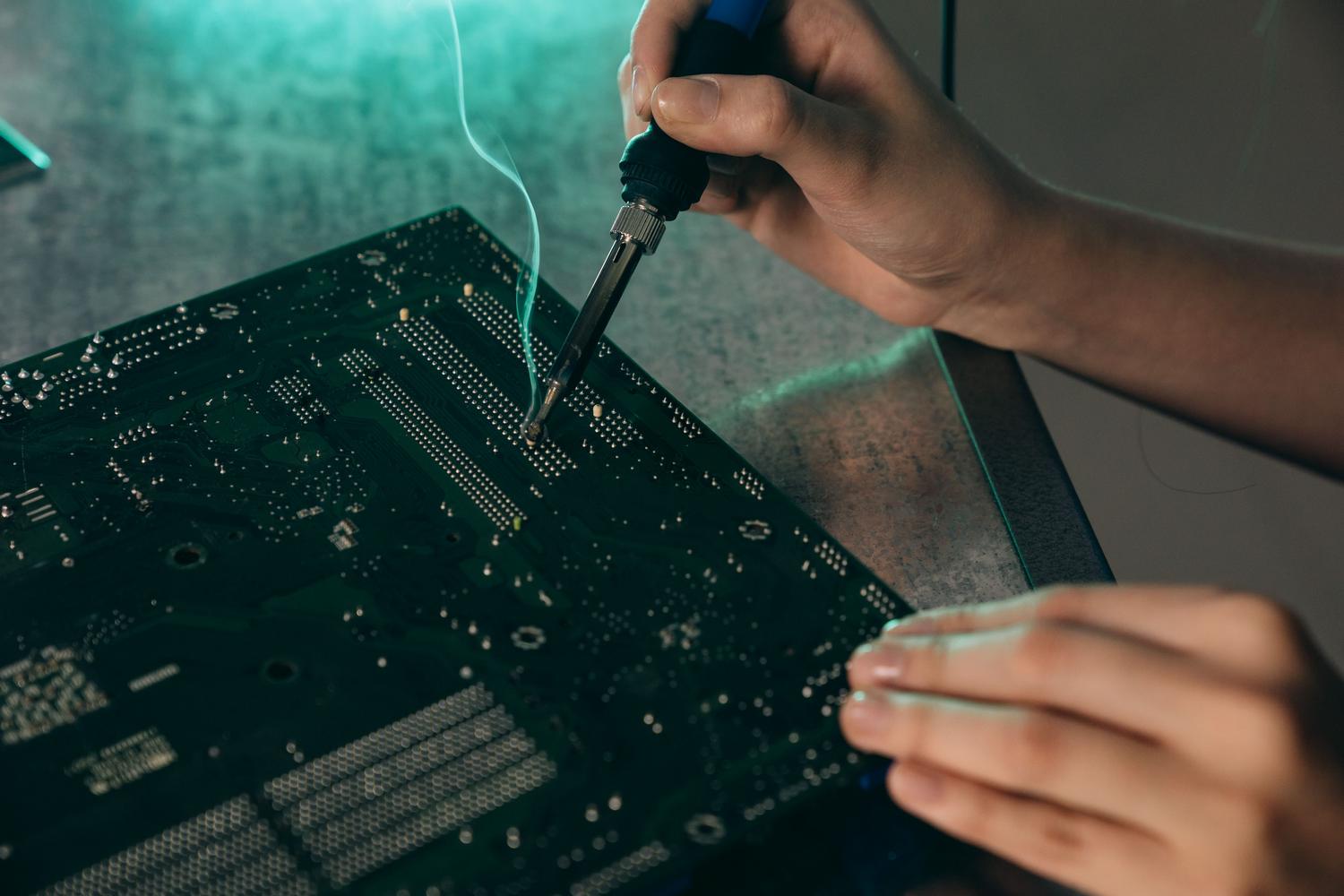 Técnico sustituyendo componentes electrónicos en una placa base mediante soldadura de precisión. Técnico sustituyendo componentes electrónicos en una placa base mediante soldadura de precisión.