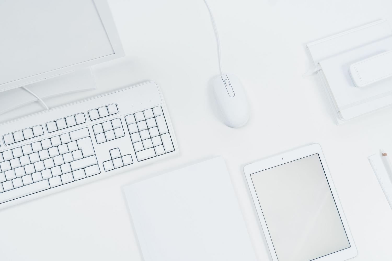 Espacio de trabajo minimalista con teclado, ratón y tableta blanca sobre un escritorio moderno. Espacio de trabajo minimalista con teclado, ratón y tableta blanca sobre un escritorio moderno.