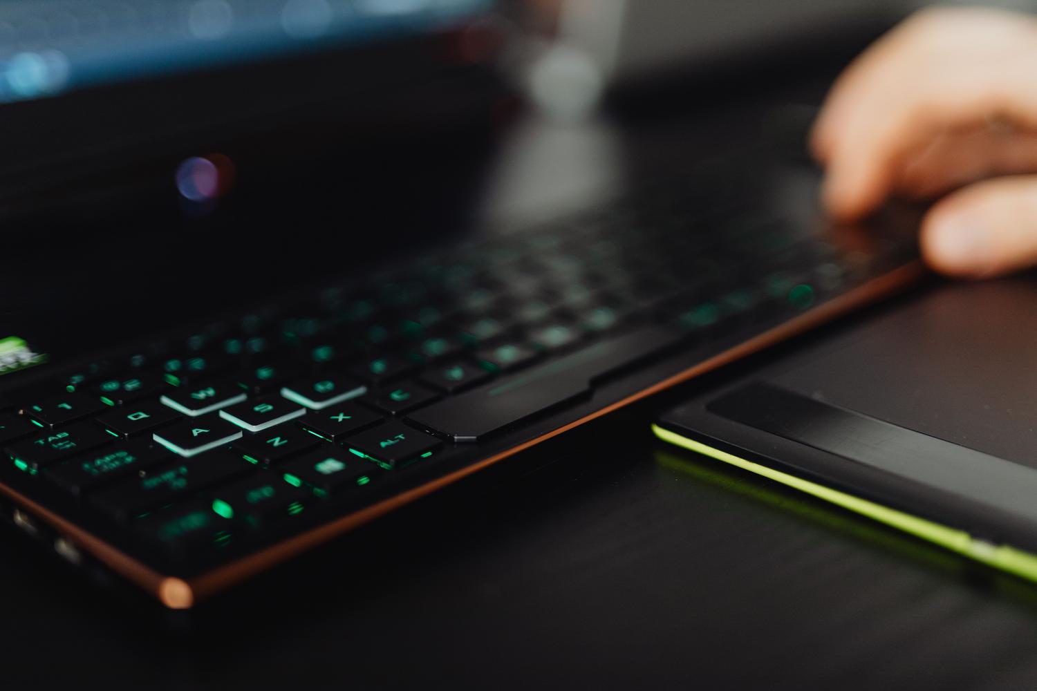 Primer plano de un teclado gaming con retroiluminación LED verde neón en un portátil. Primer plano de un teclado gaming con retroiluminación LED verde neón en un portátil.