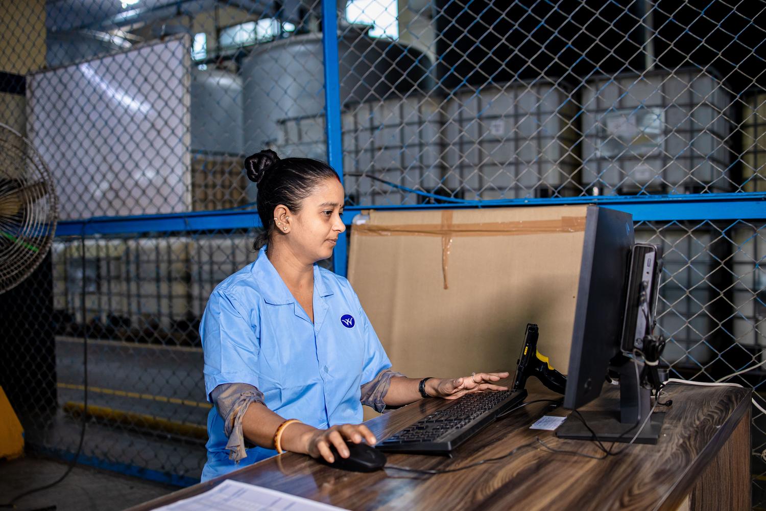 Operaria industrial utilizando un ordenador en un entorno de almacén, representando el perfil profesional que implementa soluciones de Soft-PLC. Operaria industrial utilizando un ordenador en un entorno de almacén, representando el perfil profesional que implementa soluciones de Soft-PLC.